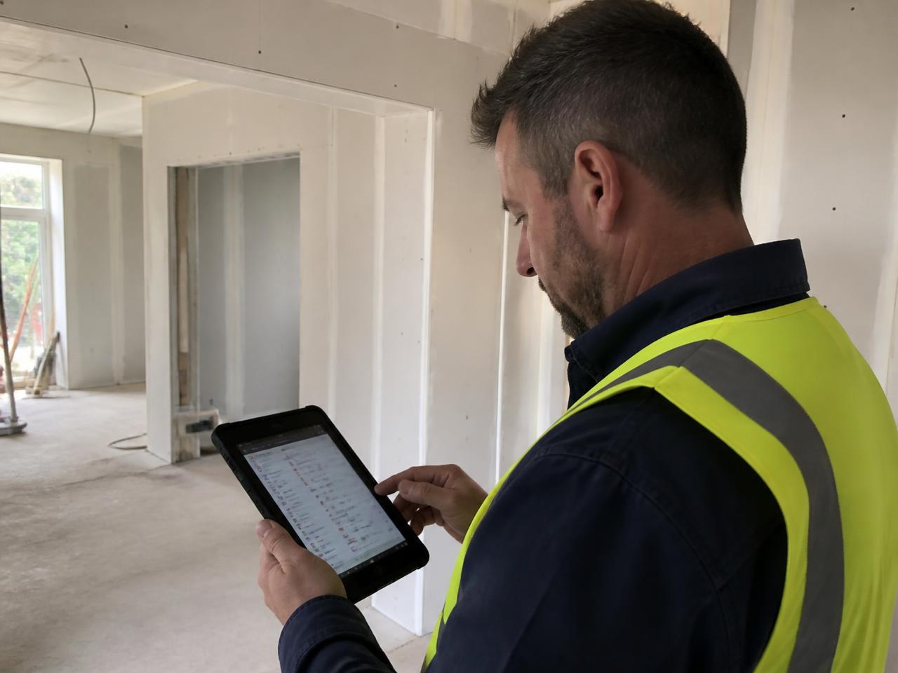 Project manager reviewing snag progress on a tablet in an unfinished interior